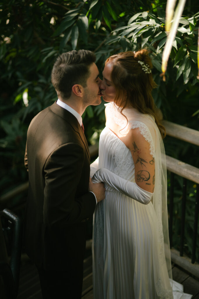 Bride and groom kissing on bride in botanic gardens