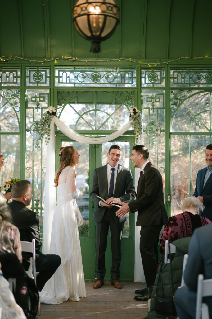 Groom laughing with bride during ceremony
