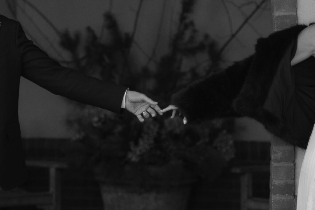 Bride and groom reaching for each other, zoomed in image of hands barely touching