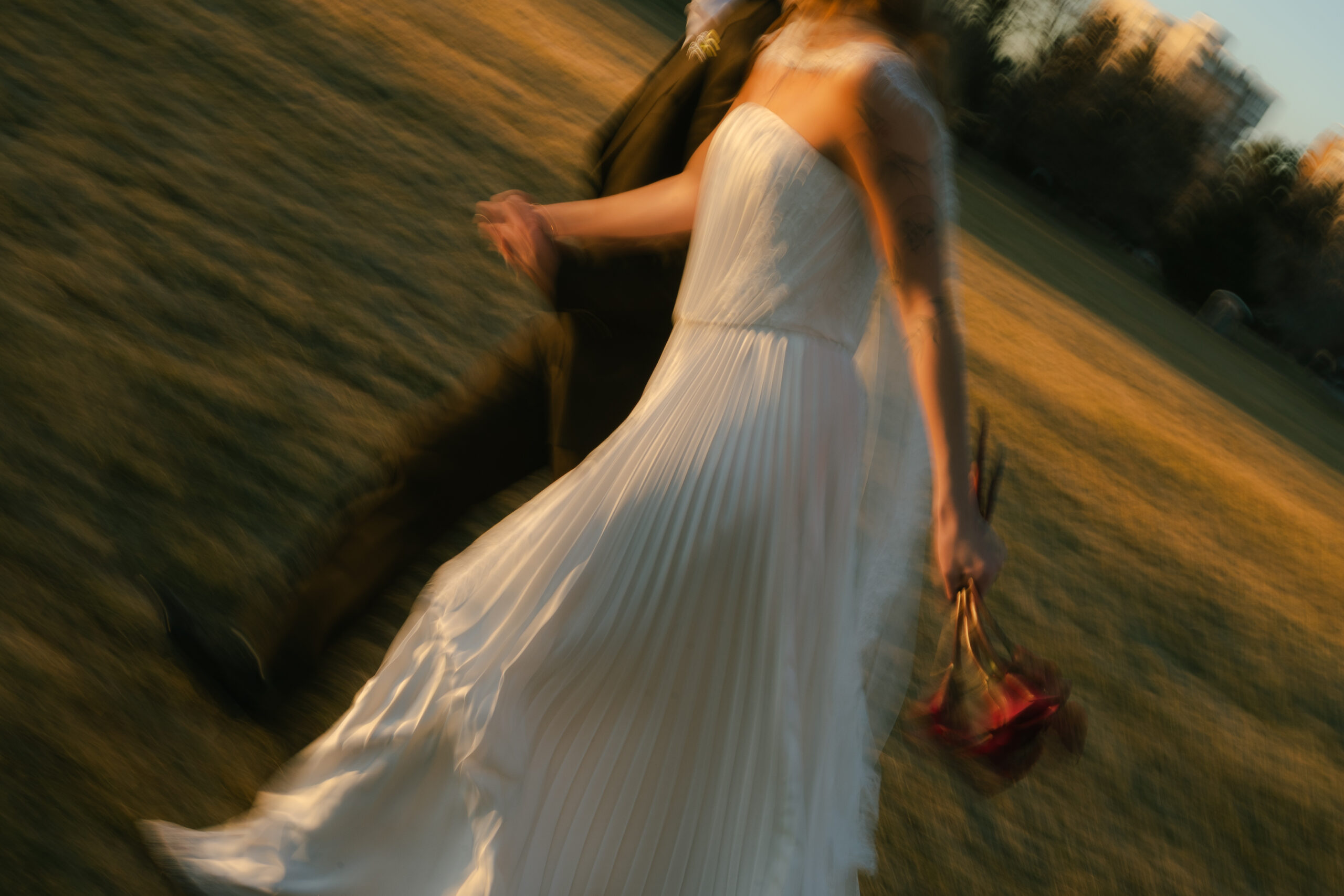 Bride and groom running during golden hour together, blurry movement photo